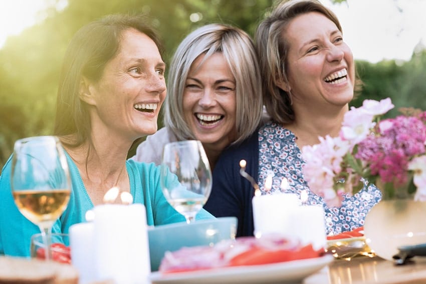 Group of middle aged woman enjoying eachothers company at a party. Each makes sure they schedule regular checkups to prevent gum disease.